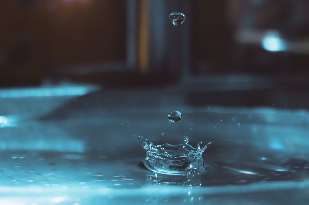 Close-up capture of water droplets splashing with a vibrant blue tone.