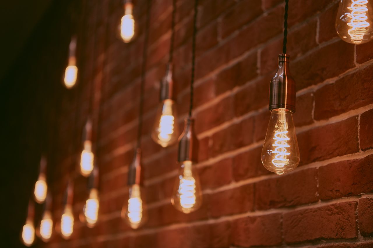 Selective focus of bright glowing lamps hanging on brick wall of modern building